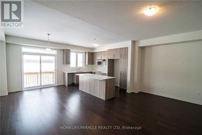 Barrie apartment for rent - A spacious living room with wooden floors and a large window.