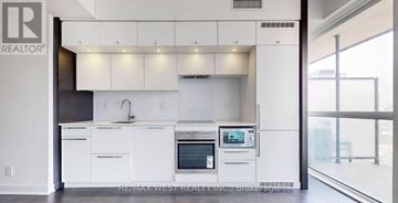 Toronto (Bay Street Corridor) condo for rent - A modern kitchen with white cabinets and appliances.