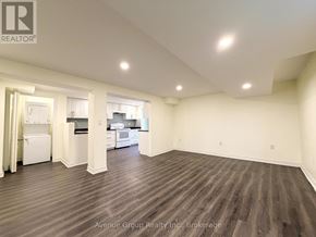 Toronto (Pleasant View) apartment for rent - A large, empty room with wood flooring and a kitchen visible through the open door.