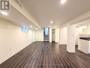 Toronto (Pleasant View) apartment for rent - A spacious room with wooden flooring and white walls, with a staircase leading to another level.