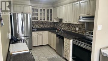 Toronto (Mount Olive-Silverstone-Jamestown) condo for rent - A kitchen with white cabinets and a black countertop.