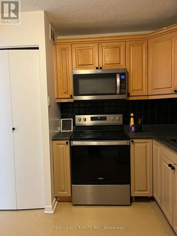 Toronto (Newtonbrook West) condo for rent - A kitchen with wooden cabinets and a black countertop.