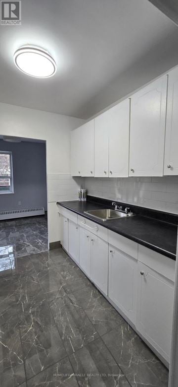 Toronto (Wexford-Maryvale) multi-family for rent - A kitchen with white cabinets and a black countertop.