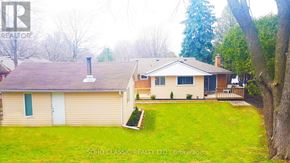 Newmarket (Huron Heights-Leslie Valley) apartment for rent - A house with a green lawn and trees in the background.