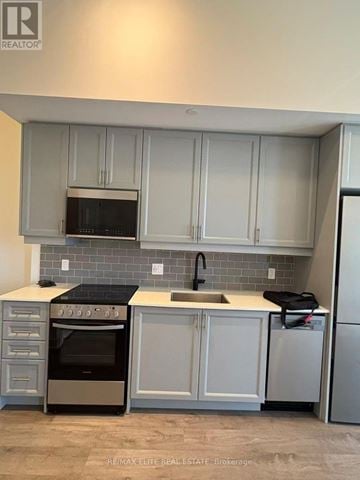 Oakville (Wm Westmount) condo for rent - A kitchen with white cabinets and a black stove top oven.