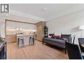 Burnaby apartment for rent - A modern kitchen with a breakfast bar and a living area with a couch and chairs.