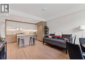 Burnaby apartment for rent - A modern kitchen with a breakfast bar and a living area with a couch and chairs.