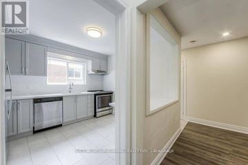 Toronto (Bathurst Manor) triplex for rent - A kitchen with white cabinets and a window.