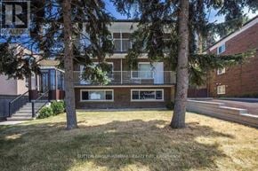 Toronto (Bathurst Manor) triplex for rent - A tree stands in front of a two-story building.