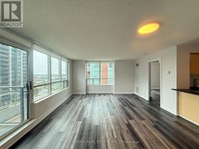 Markham (Commerce Valley) condo for rent - A spacious room with wood flooring and large windows overlooking a cityscape.