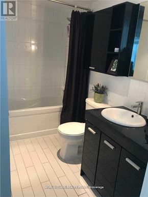 Toronto (Bayview Village) condo for rent - A bathroom with a toilet, sink, and black cabinetry.
