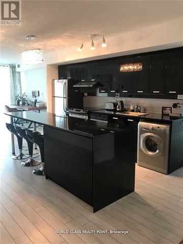 Toronto (Bayview Village) condo for rent - A modern kitchen with black cabinets and a central island.