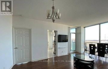 Mississauga (City Centre) house for rent - A living room with a white door, a television, and a dining table with chairs.