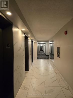 Toronto (Victoria Village) condo for rent - A long hallway with marble floors and walls.