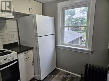 Welland (Welland Downtown) triplex for rent - A kitchen with a white fridge and black stove top.