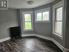 Welland (Welland Downtown) triplex for rent - A room with grey walls and wooden flooring with a window and a radiator.