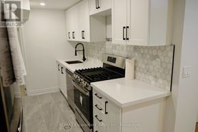 Toronto (Regent Park) townhouse for rent - A modern kitchen with a stove top oven and a white counter top.