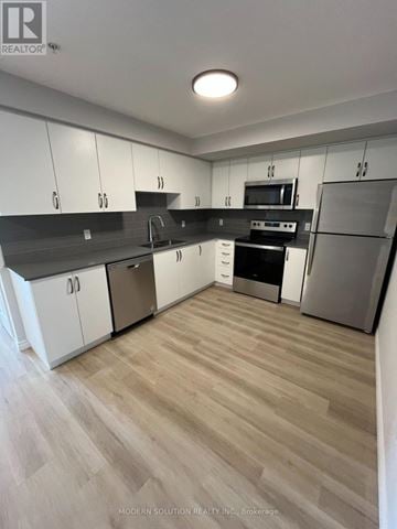 Guelph (Grange Road) condo for rent - A modern kitchen with white cabinets and stainless steel appliances.