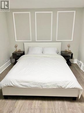 Niagara Falls (Cherrywood) multi-family for rent - A white bed with a white headboard and two small tables with objects on them.