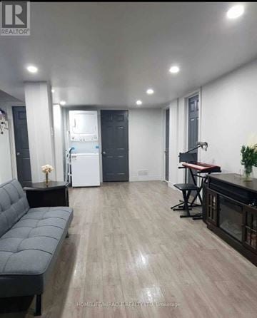 Vaughan (Elder Mills) apartment for rent - A modern living room with a grey sofa and a kitchen area in the background.