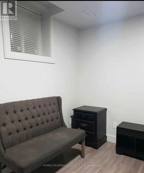 Vaughan (Elder Mills) apartment for rent - A brown tufted couch sits in a room with a small black table and a black cabinet.