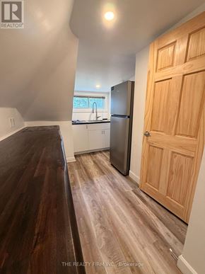 London East (East M) duplex for rent - A kitchen with a refrigerator, sink, and wooden floors.