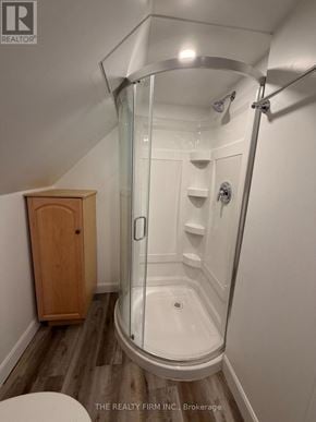 London East (East M) duplex for rent - A shower with a glass door and a wooden cabinet.