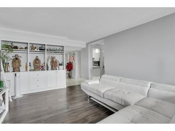 Gatineau (Hull) condo for rent - A living room with a white couch and a wall of shelves with various decorations.