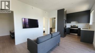 Vancouver apartment for rent - A living room with a grey couch and a television on the wall.