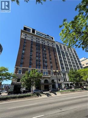 Hamilton condo for rent - A tall building with a brown brick facade stands on a street corner.
