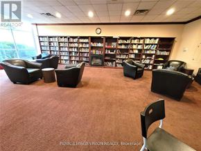 Toronto (Banbury-Don Mills) condo for rent - A room with a carpeted floor, a bookshelf filled with books, and several black leather chairs.