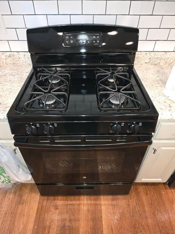 Austell apartment for rent - A black stove top oven with four burners and a digital display is in a kitchen.
