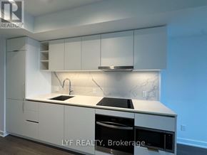Toronto (Bay Street Corridor) condo for rent - A modern kitchen with white cabinets and a marble backsplash.