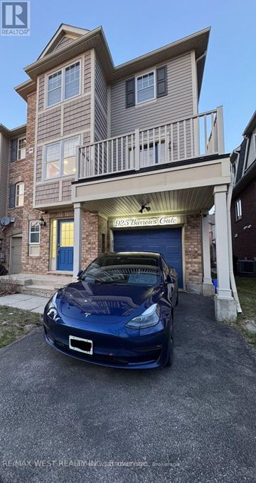 Milton (Co Coates) townhouse for rent - A blue car is parked in front of a two-story building with a garage.