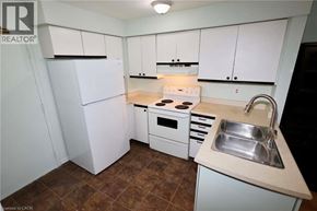 Kitchener townhouse for rent - A small kitchen with white cabinets and brown tiles.
