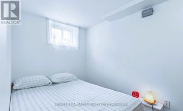 Toronto (Wexford-Maryvale) apartment for rent - A small bedroom with a bed, pillows, a window, and a nightstand with a lamp.