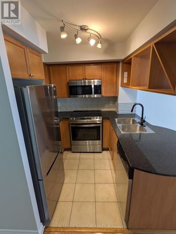 Mississauga (City Centre) condo for rent - A kitchen with wooden cabinets and a stainless steel refrigerator.