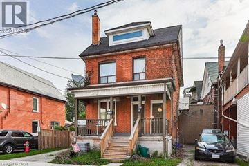 Hamilton apartment for rent - A red brick house with a black car parked in front.