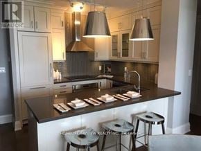 Markham (Angus Glen) condo for rent - A modern kitchen with a black countertop and white cabinets.