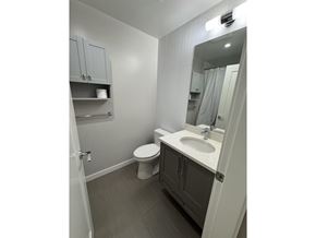 Langley apartment for rent - A bathroom with a toilet, sink, and mirror.