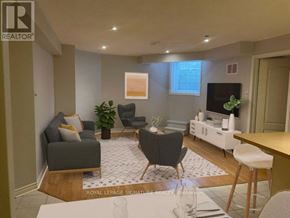 Mississauga (Churchill Meadows) apartment for rent - A living room with a grey couch, a black chair, a white coffee table, and a TV on the wall.
