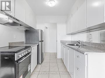 Toronto (Weston) condo for rent - A kitchen with white cabinets and a black stove top oven.