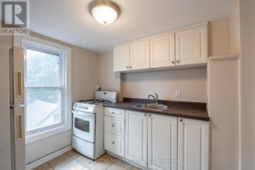 Hamilton (Stipley) duplex for rent - A kitchen with white cabinets and a black stove top.