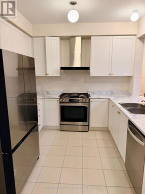 Oshawa (Kedron) apartment for rent - A kitchen with white cabinets and a black refrigerator.