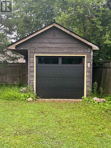 Georgina (Virginia) apartment for rent - A small wooden garage with a black door is surrounded by a grassy area and a wooden fence.