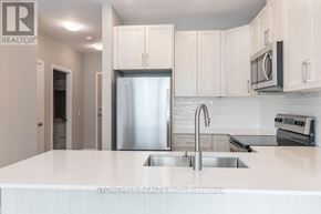 Kitchener condo for rent - A modern kitchen with a stainless steel refrigerator and white countertops.