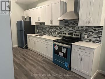 London East (East K) multi-family for rent - A kitchen with white cabinets and a black refrigerator.