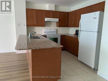 Barrie (City Centre) condo for rent - A kitchen with brown cabinets and a white refrigerator.
