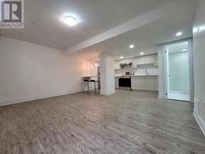 Mississauga (Churchill Meadows) apartment for rent - A spacious room with wood flooring and a kitchen area in the background.