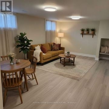 Burlington (Appleby) apartment for rent - A living room with a brown couch, a wooden coffee table, and a dining table with chairs.